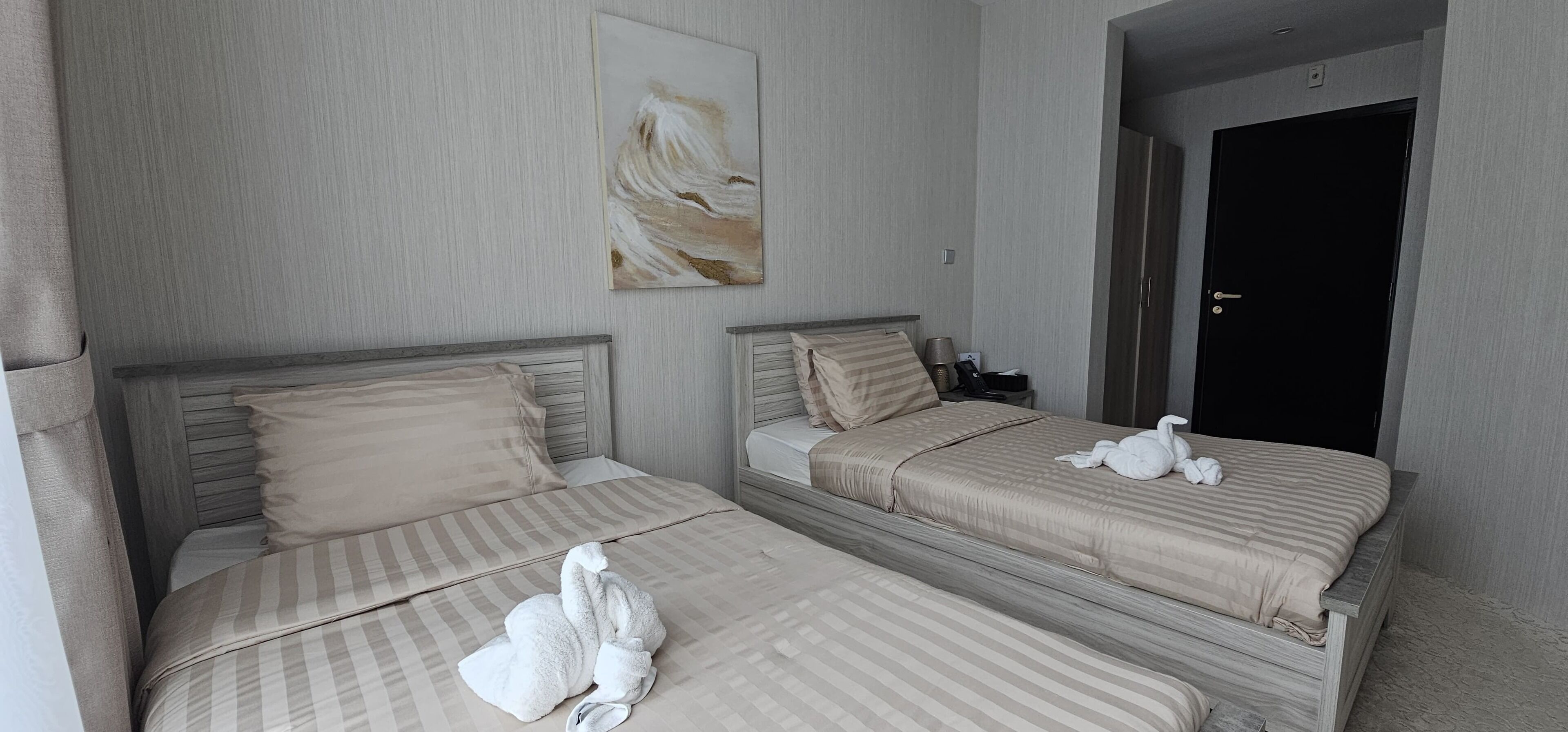 Una habitación de hotel con dos camas, un cuadro en la pared y una puerta.