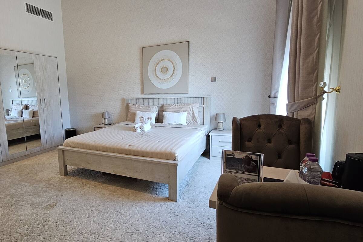 Ein Hotelzimmer mit Bett, Schrank, Nachttisch, Stuhl und einem großen Spiegel.
