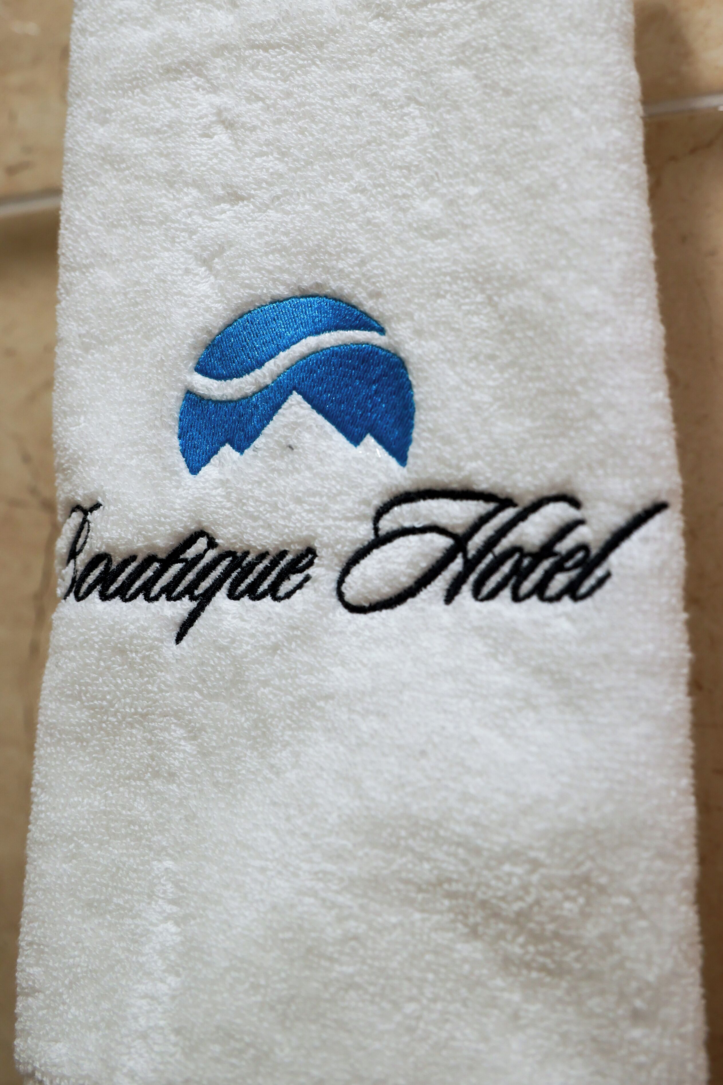 A white towel with a logo and the text 'Boutique Hotel' embroidered on it.