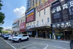 A multi-story building with various commercial establishments on the ground floor, including a hotel with a visible sign. - Memory Hotel (Zhenjiang)