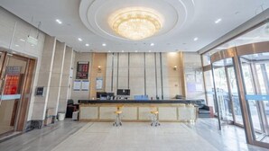 A modern hotel lobby with a central reception desk, a large chandelier, and a glass entrance. - Memory Hotel (Zhenjiang)