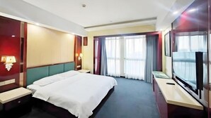 A hotel room with a large bed, a TV, a desk, and a window with curtains. - Memory Hotel (Zhenjiang)