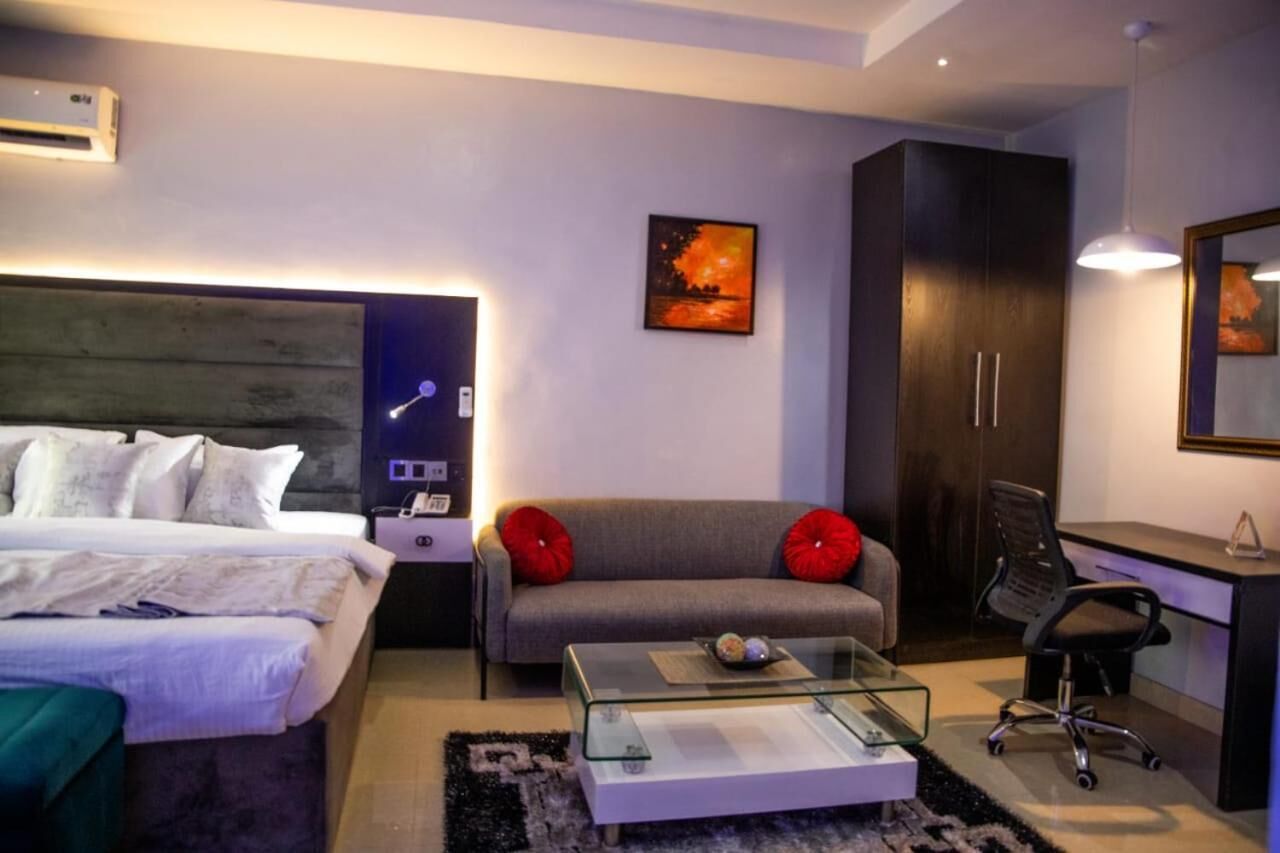 Une chambre d’hôtel moderne équipée d’un lit, d’un canapé, d’un bureau et d’une table basse en verre.