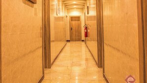 Un pasillo con paredes y suelos de mármol, que conduce a una puerta de madera al final.
