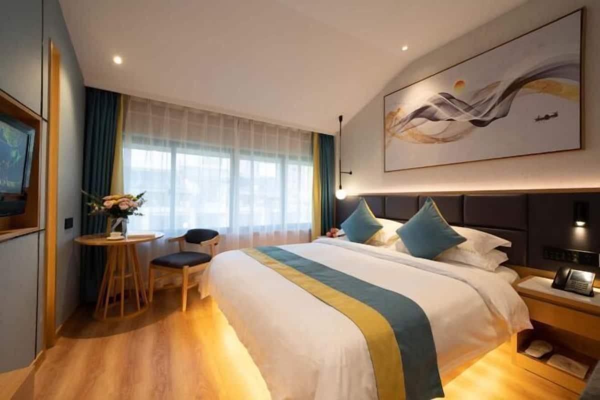 Et hotelværelse med en seng, et natbord, en lampe og et billede på væggen.