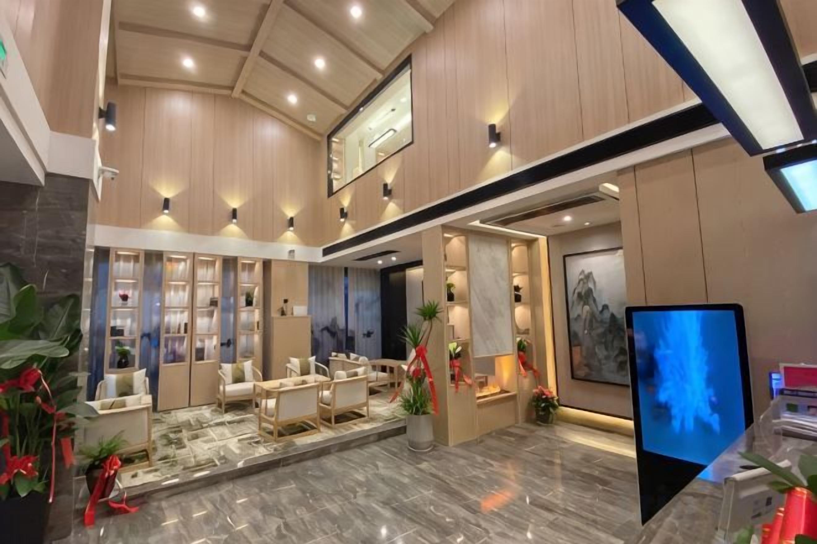 Vestíbulo de hotel con mostrador de recepción, zona de estar y una pantalla digital grande.