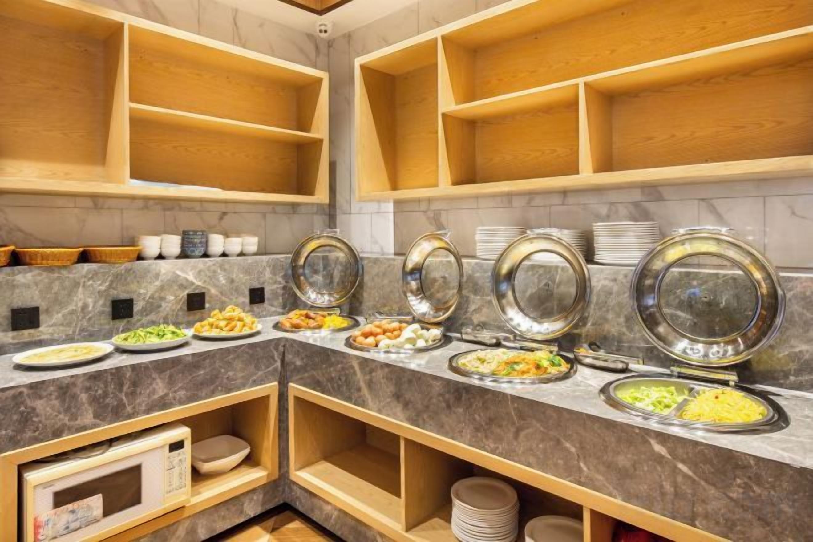 Montaje tipo bufé con varias estaciones de comida, estantes de madera y una encimera de mármol.