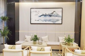 Ein modernes Interieur mit einer Couch, Sesseln, einem Tisch und einem gerahmten Kunstwerk an der Wand.