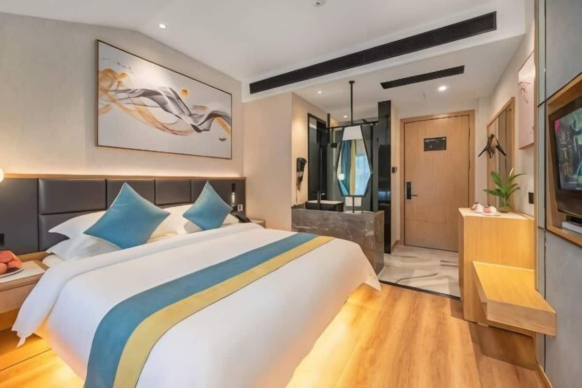 Et moderne hotelværelse med en stor seng, et skrivebord, et spejl og et fjernsyn.