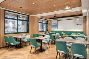 A modern dining area with wooden paneling, large windows, and green upholstered chairs. - Outing Boutique Hotel Yiwu International Trade City (Yiwu)