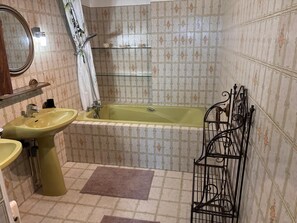 Une salle de bain équipée d’un lavabo, d’un miroir, d’une baignoire et d’une étagère en métal.