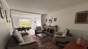 Una sala de estar con dos sofás, una mesa de centro y una chimenea. Se ve un comedor a través de una puerta abierta.