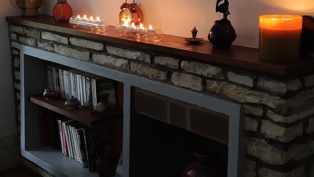 Una sala de estar acogedora con chimenea de piedra, una estantería y un cuadro con una cebra.