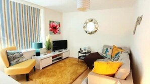 Ein Wohnzimmer mit einer Couch, einem Couchtisch, einem Fernseher und einem dekorativen Spiegel.