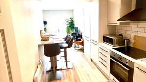 Une cuisine moderne équipée d’un four à micro-ondes, d’un four traditionnel et de meubles blancs.