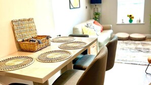 Un coin repas avec une table en bois, des sets de table en fibres tressées et un panier en osier.