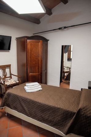 A bedroom with a bed, a wooden wardrobe, a chair, and a flat-screen TV mounted on the wall. - Dimora del Borgo Affittacamere (Sangineto)