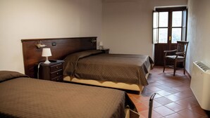 Un dormitorio con dos camas, una silla, una mesita de noche y una ventana.