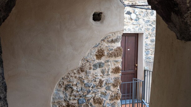 Un estrecho pasaje con un muro de piedra y una puerta de madera.