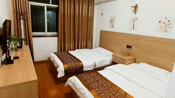 Hotellihuone, jossa on kaksi sänkyä, puinen työpöytä, ikkuna verhoilla ja seinälle kiinnitetyt taideteokset.