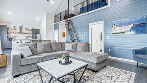 A modern living room with a grey sectional sofa, a marble coffee table, and a patterned rug.