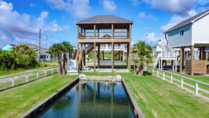 A waterfront property with a covered deck, a swimming pool, and a small boat dock.