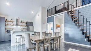 A modern kitchen with wooden cabinets, a central island, and a dining area with a wooden table and chairs.