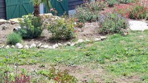 A garden with various plants and a wooden deck. - Gite Cosy Dans un Cadre Verdoyant Entre Méditerranée et Gorges du Verdon (Flassans-sur-Issole)
