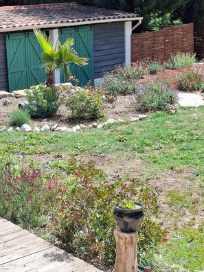 Um jardim com diversas plantas e um deck de madeira.