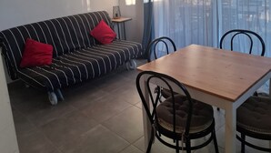 A living room with a sofa, a dining table, and chairs. - Gite Cosy Dans un Cadre Verdoyant Entre Méditerranée et Gorges du Verdon (Flassans-sur-Issole)