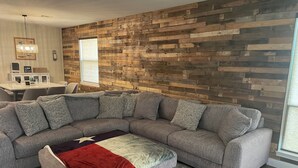 A modern living room with a sectional sofa, a red throw blanket, and a wooden wall panel.