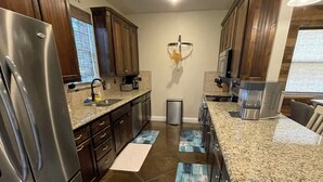 A modern kitchen with stainless steel appliances, dark wooden cabinets, and a granite countertop.