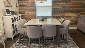 A dining area with a wooden wall, a large window, and a chandelier.