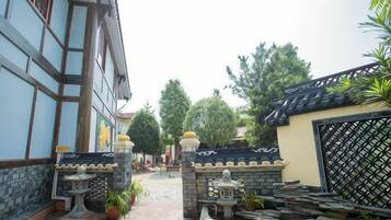 A courtyard with a tiled pathway, stone lanterns, and potted plants.