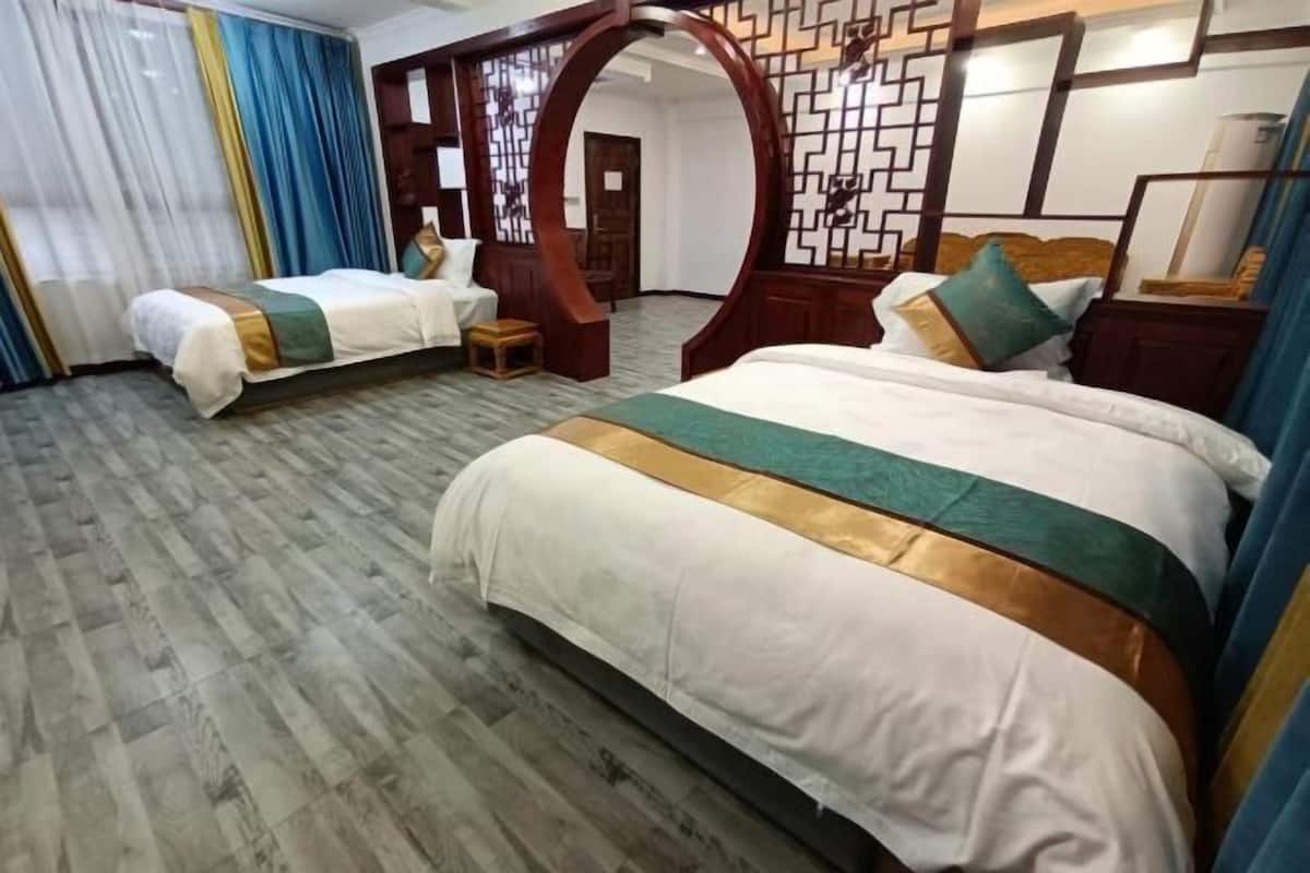 Une chambre d’hôtel avec un grand lit, un lit plus petit, une arche en bois et un panneau décoratif au mur.
