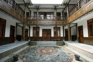 A traditional courtyard with a central tiled floor, wooden doors, and a balcony with intricate railings. - Yiyi Hotel (Dujiangyan)