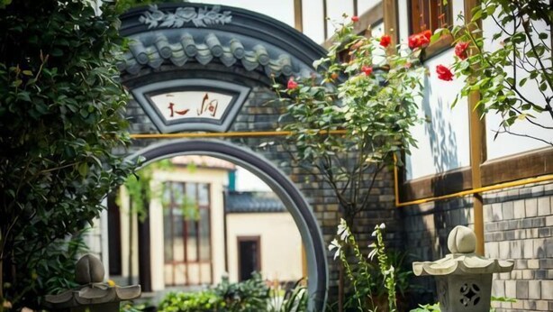 A traditional gate with a circular archway, a stone lantern, and lush greenery. - Yiyi Hotel (Dujiangyan)