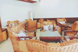 A room with wicker furniture, including sofas and armchairs, arranged around a central table. - Yiyi Hotel (Dujiangyan)