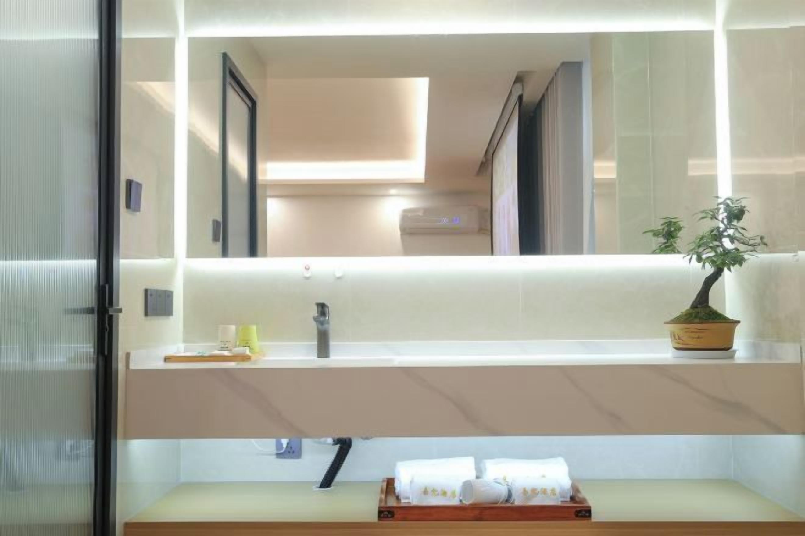 Un baño moderno con espejo, lavamanos y toallero.