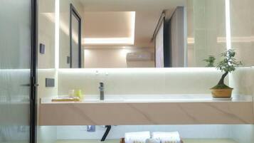 Un baño moderno con espejo, lavamanos y toallero.