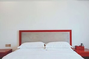 A bed with a red frame and white bedding in a room with white walls.