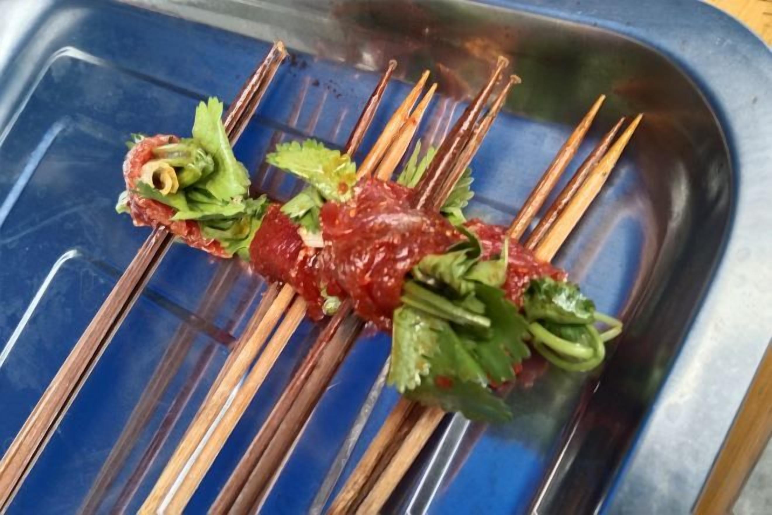 Skewers with meat and vegetables on a blue tray.