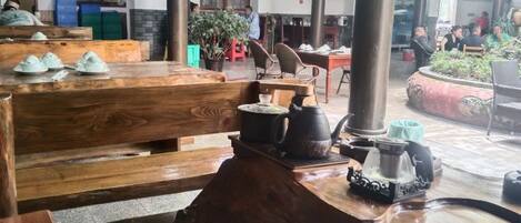 Un comedor tradicional de madera con bancos y mesas, un juego de té y una planta en maceta.