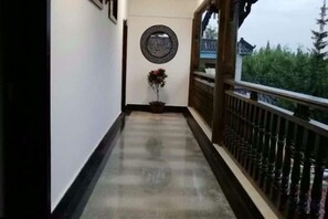A corridor with a potted plant, a circular wall decoration, and a balcony with a railing. - Yiyi Hotel (Dujiangyan)