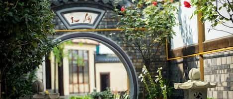 A traditional archway with Chinese characters, surrounded by lush greenery and a stone lantern.