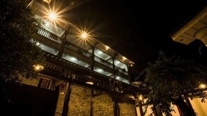 A multi-story building with balconies, illuminated by exterior lights, and surrounded by trees. - Yiyi Hotel (Dujiangyan)