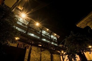 A multi-story building with balconies, illuminated by exterior lights, and surrounded by trees. - Yiyi Hotel (Dujiangyan)
