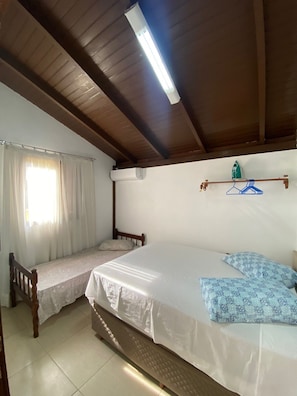 A room with a bed, a bench, a hanging clothes rack, and a window with curtains. - Brusque Comfort Studio (Brusque)