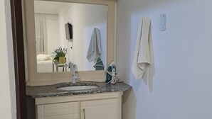 Un baño con lavamanos, espejo y barra para toallas.