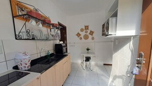 Una cocina compacta con encimera negra, armarios de madera, una pequeña mesa con sillas y un microondas.